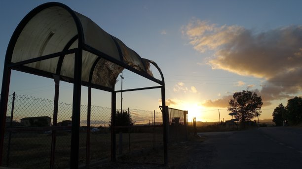 日落时分，郊区一个被毁一半的公交车站图片下载