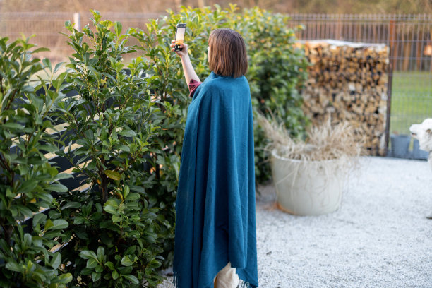 穿格子花呢的女人在后院用手机拍日落图片下载