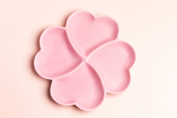空粉红色盘子形式的四个心在粉彩背景。从以上观点。图片下载