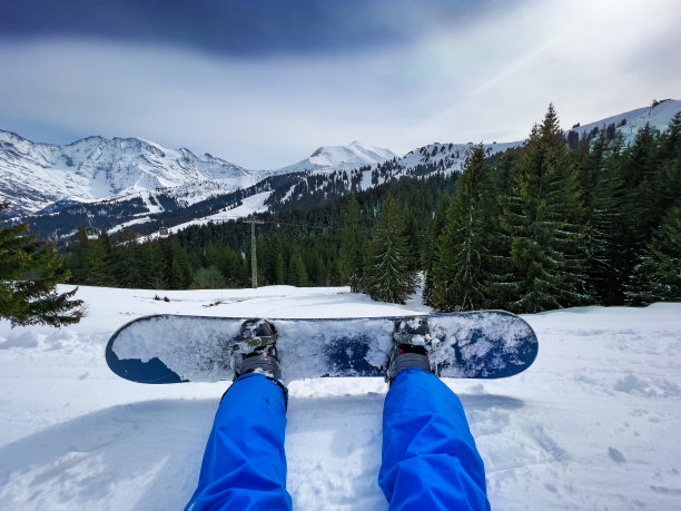 坐在滑雪缆车上的男子，腿固定在滑雪板上图片下载