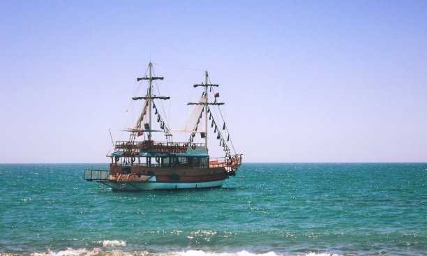 一艘沿着海岸在海上散步的小游艇。图片下载