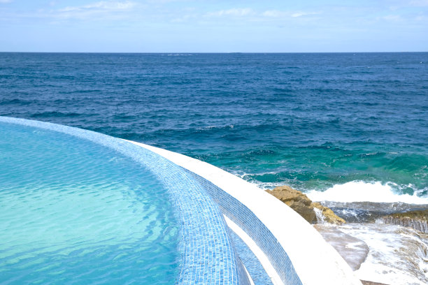 蓝色清澈的水面游泳池在一个度假胜地的海景。暑假和休息的概念。豪华海滩别墅。蓝色瓷砖马赛克图案。图片下载