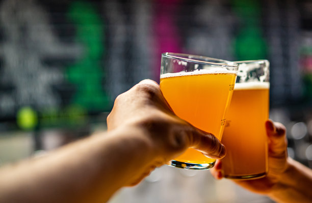 手中的两杯啤酒，在酒吧或酒馆里碰杯图片下载