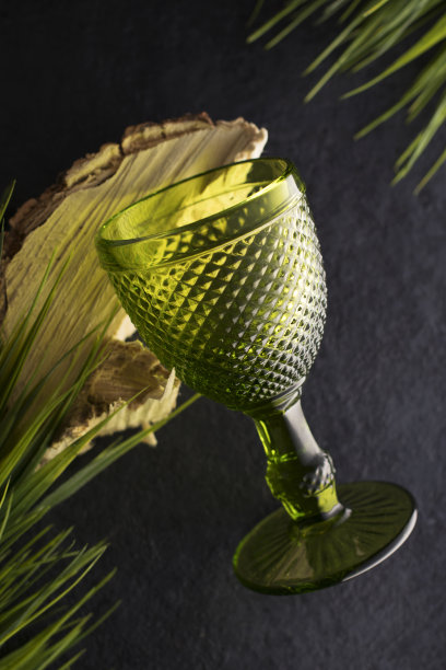 木质背景上的绿色玻璃杯和树叶，生态餐桌摆设概念，竖版照片图片下载