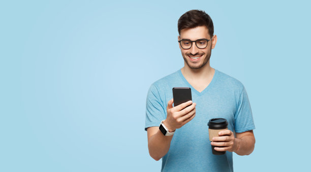 横幅上年轻微笑的男人拿着外卖咖啡杯，检查新的信息在电话图片下载