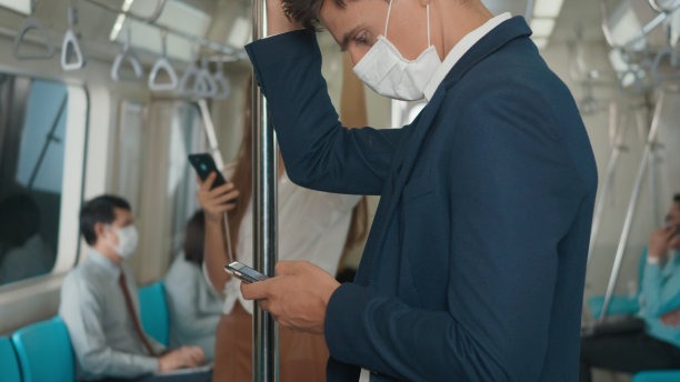 商人站在座位上，用现代智能手机上网，在电动火车上查看新闻图片下载