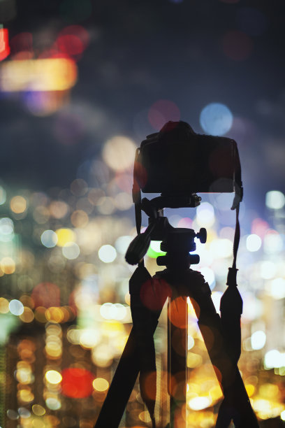 三脚架上的专业相机，俯瞰夜晚的城市灯光，拍照图片下载