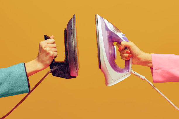 波普艺术摄影。彩色形象的女性手握现代和老式熨斗孤立在明亮的黄色背景图片下载