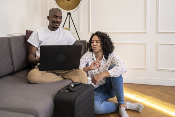 一对非洲裔夫妇一边看着笔记本电脑一边聊天图片下载