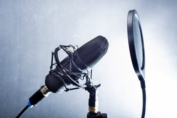 特写的一个专业麦克风与流行过滤器在前面。桌面麦克风录制播客，歌曲和流媒体对一个黑暗的背景图片下载
