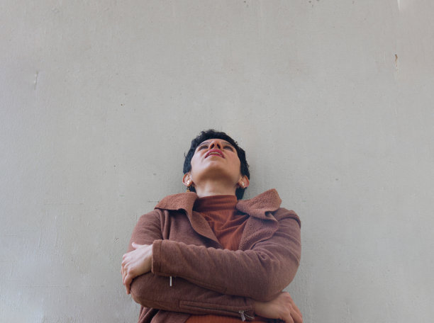 一个短头发的女人，双臂交叉，抬头看着前面单色的背景图片下载