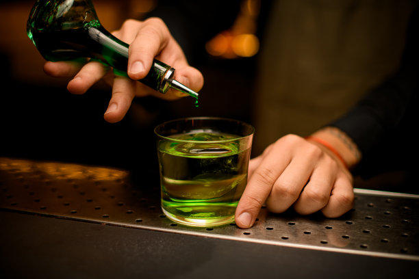 瓶体特写，滴一滴绿色香精到玻璃杯中就成了鸡尾酒图片下载