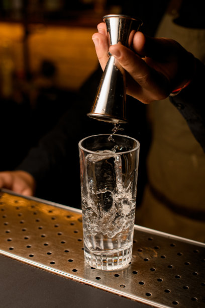 透明玻璃上有冰块，男人们用手从酒桶里倒出饮料图片下载