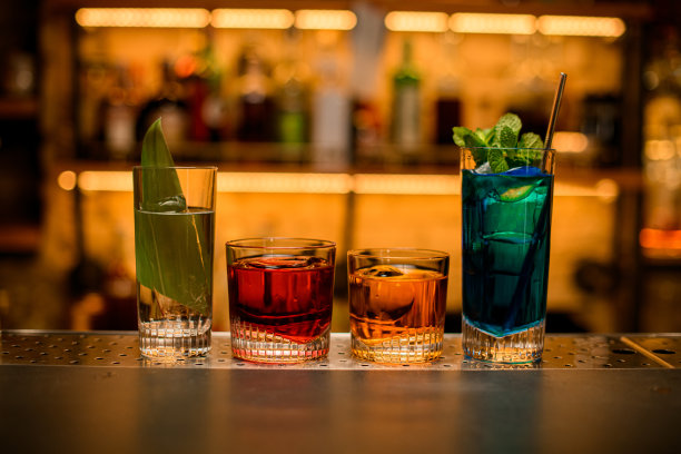 酒吧柜台上一组彩色鸡尾酒玻璃杯的正面视图。图片下载