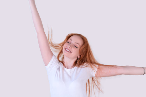 一个头发蓬乱的年轻女子伸展在一个浅色的背景上图片下载