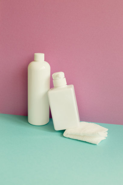 薄荷绿桌子上的护肤皂、洗发水瓶、浴巾，粉色墙壁背景，浴室用品图片下载