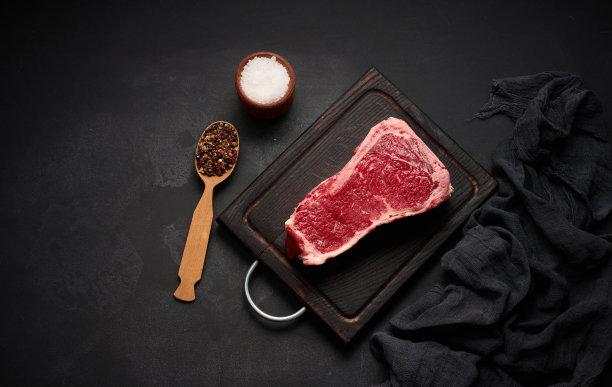 新鲜的生牛肉片，黑底上的牛排，俯视图。有大理石花纹的肉图片下载