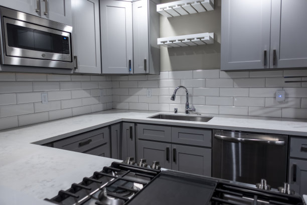 从角度看，一个白色的、空的厨房，大理石台面和一个煤气炉，在背景中的水龙头图片下载