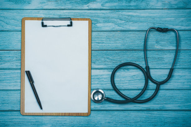 病史与听诊器和剪贴板的木制书桌背景。图片下载