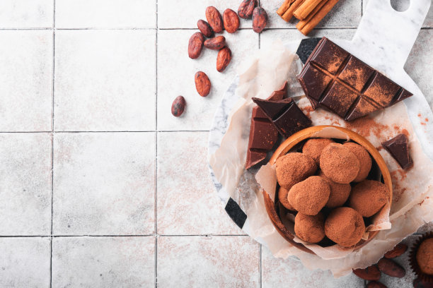 巧克力松露与可可粉在木制盘子在旧裂瓦桌子背景。美味甜美的巧克力松露糖果。情人节和母亲节的概念与拷贝空间。前视图。图片下载