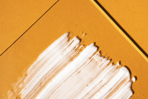 白色防晒霜在明亮的橙色背景上，俯视图。夏季防晒产品，近距离涂抹。图片下载