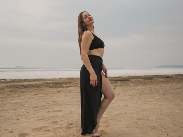 赤足的红发女子穿着黑色晚礼服在沙滩上跳探戈图片下载