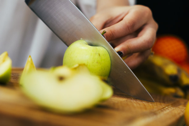 特写:一把刀在厨房的木板上把一个青苹果切成两半。健康的生活。有机食品。股票的照片。图片下载