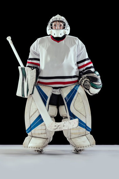 全身肖像的男孩，孩子，曲棍球运动员在特殊的制服守门员摆出孤立的黑色工作室背景图片下载