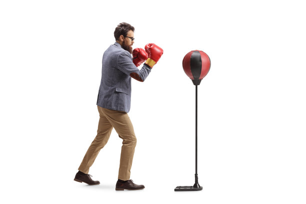 一个休闲男子锻炼与拳击手套和一个自由站立punch bag全长资料拍摄图片下载