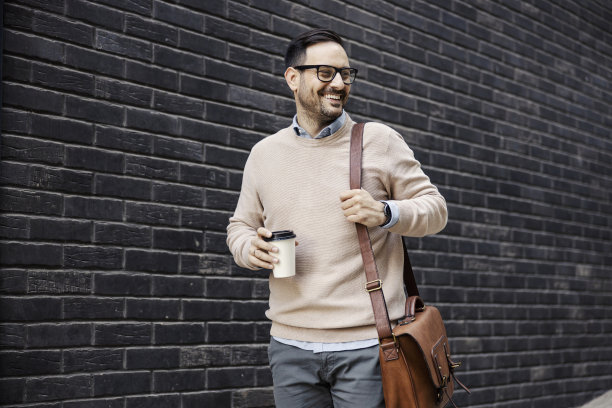 一个快乐时髦的男人走在街上，一边喝咖啡一边去上班。图片下载
