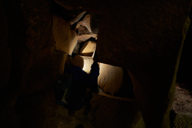 游客一边打着手电筒一边研究洞穴墙壁图片下载