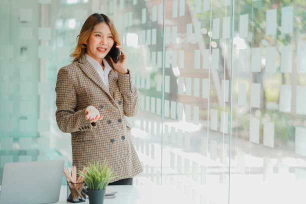 快乐微笑的亚洲女商人通过智能手机谈生意，在家通过互联网在线工作。使用手机与客户沟通图片下载