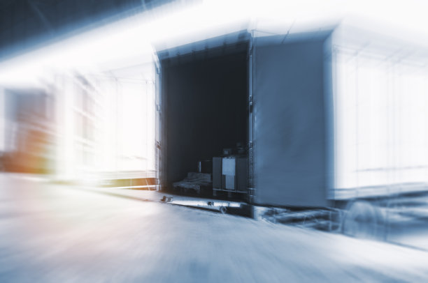 模糊显示停靠在码头仓库装载货物的卡车。货物供应链。配送货车运输物流图片下载