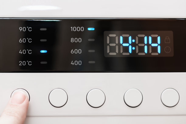 洗衣机显示关闭，洗涤过程中剩余时间4小时14分钟。手指选择清洗模式。抽象洗衣编程背景图片下载