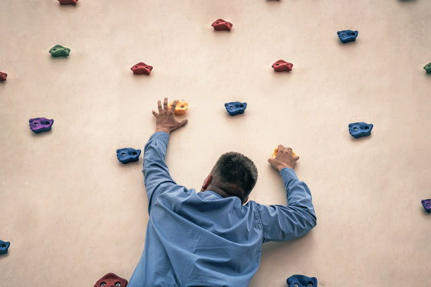 打着领带的商人在攀岩。把攀岩作为业余爱好。办公室职员在健身房训练。极限运动。图片下载