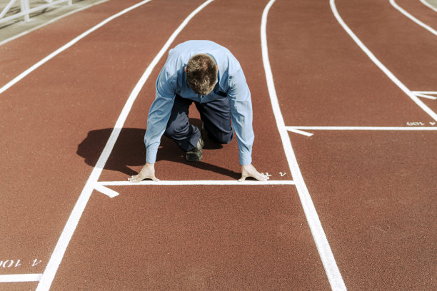 年轻的商人站在开始姿势准备逃跑。启动业务。职业生涯的开始。一名上班族在体育场训练。图片下载
