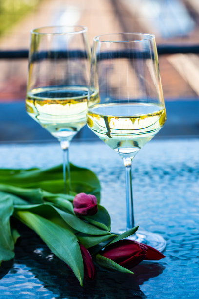 两个酒杯放在放着郁金香的玻璃桌上图片下载