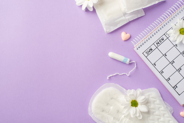 俯视图照片的日历期间垫卫生棉条甘菊芽和小心脏上孤立的淡紫色背景与copyspace图片下载
