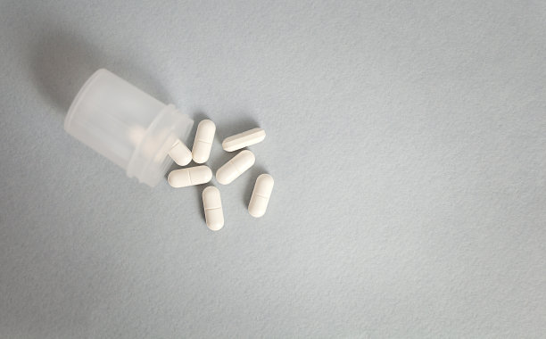 灰色的桌子上放着一个塑料容器，里面散落着药片图片下载