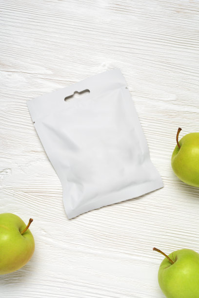 白色塑料袋装苹果放在木桌上。图片下载
