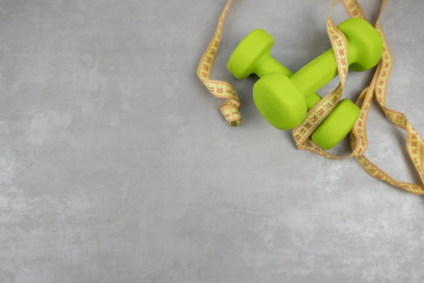 哑铃，灰色纹理背景上的卷尺。健身、运动营养图片下载