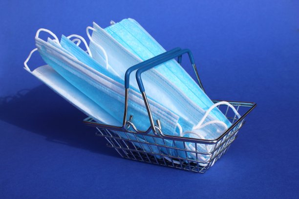医用口罩放在蓝色背景下的小型购物篮里。图片下载
