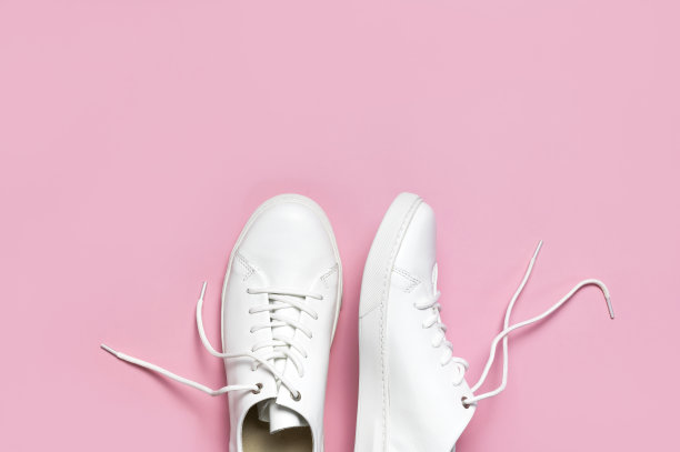 白色妇女的皮革运动鞋在粉红色背景顶视图平lay。时尚青年运动鞋，运动鞋，真皮鞋履。简约的鞋店广告时尚风格的鞋子背景图片下载
