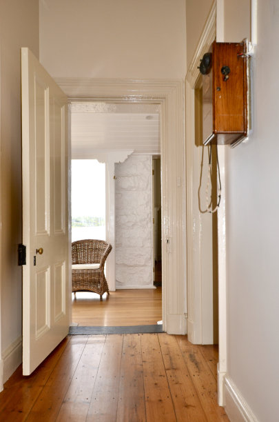 古老的别墅走廊在晨光中，波罗的海松木地板，一把旧柳条椅和墙上的老式电话图片下载