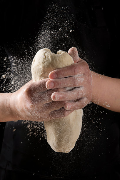 烘焙的概念。双手在黑色背景上揉面团图片下载