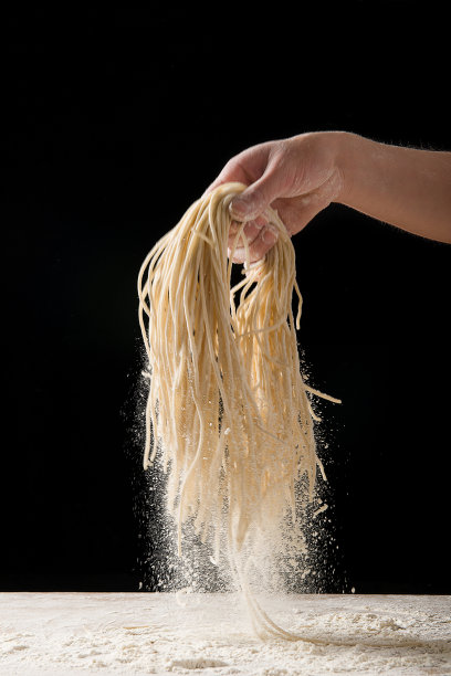 手握面条在黑色背景图片下载