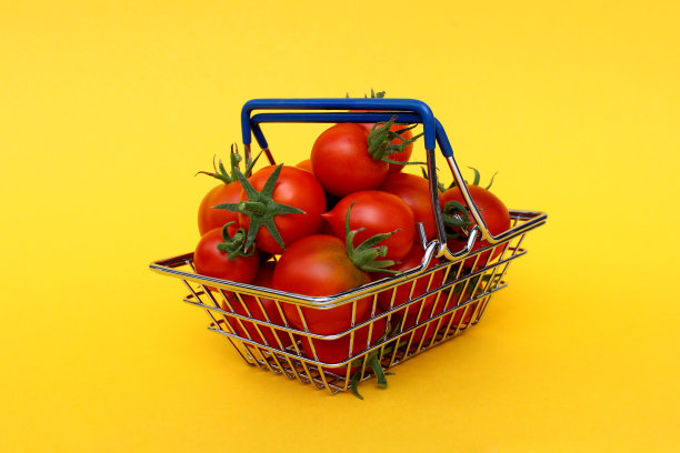 黄色背景下篮子里的番茄特写镜头图片下载