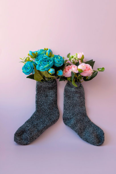 两只灰色温暖的袜子在粉红色的背景上，里面有粉红色和蓝色的花束图片下载