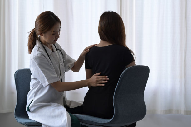 专业理疗师在医疗诊所检查背部受伤的女性病人的照片。图片下载
