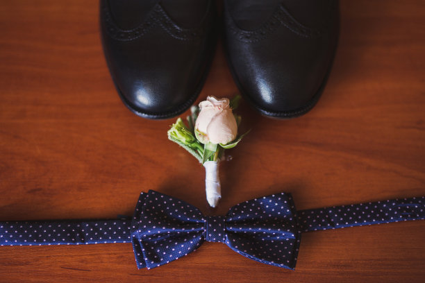 一套新郎领结，胸花，和鞋子躺在木制背景。图片下载